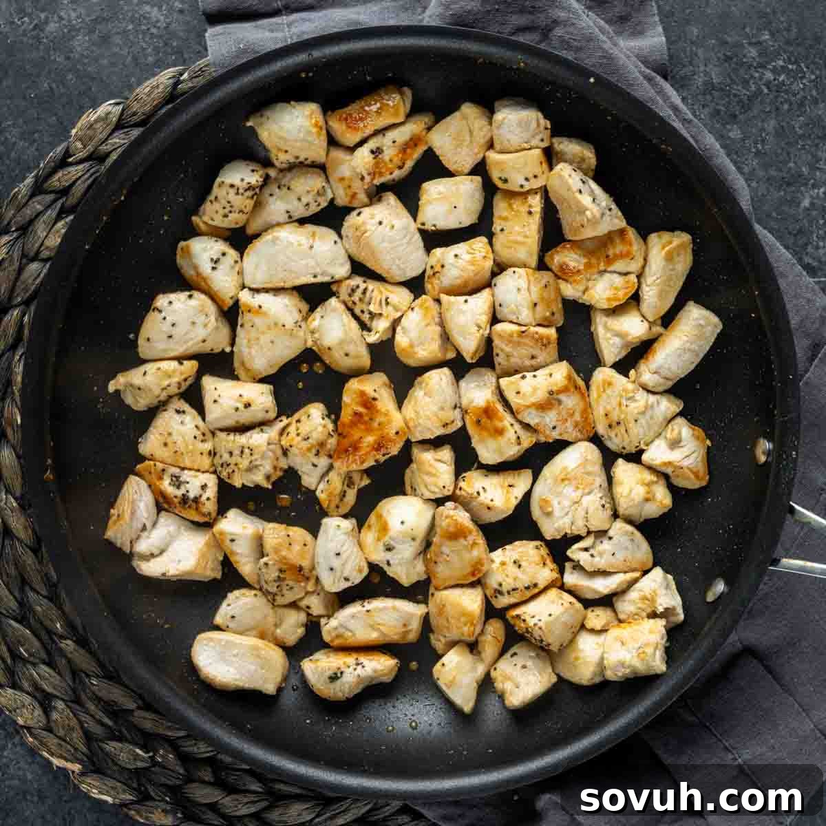 Diced chicken breast pieces sizzling and browning in a hot frying pan, seasoned with salt and pepper, ready for the Chicken Florentine Pasta.