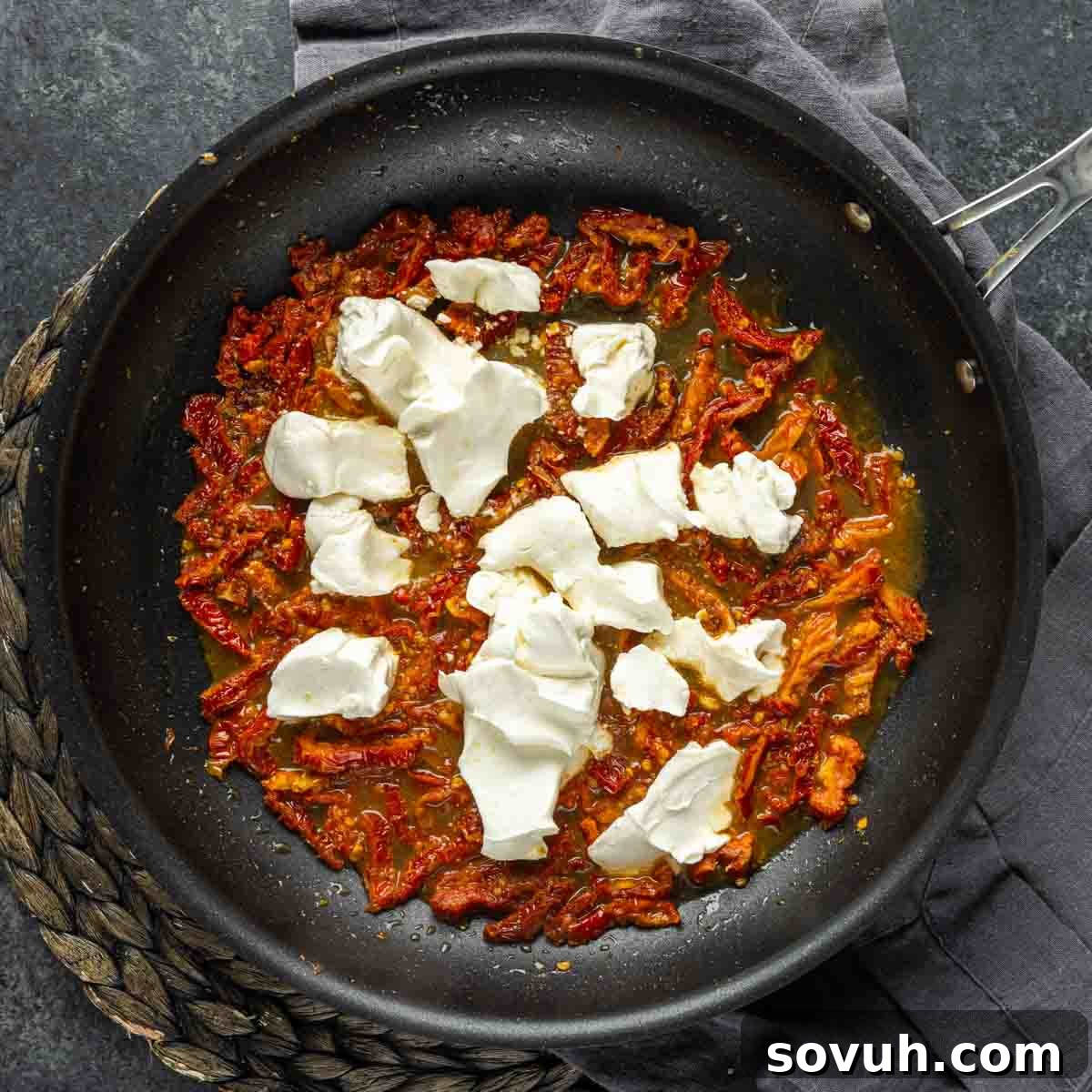 Rich, simmering tomato sauce dotted with melting cream cheese in a skillet, forming the base for the decadent Chicken Florentine Pasta.