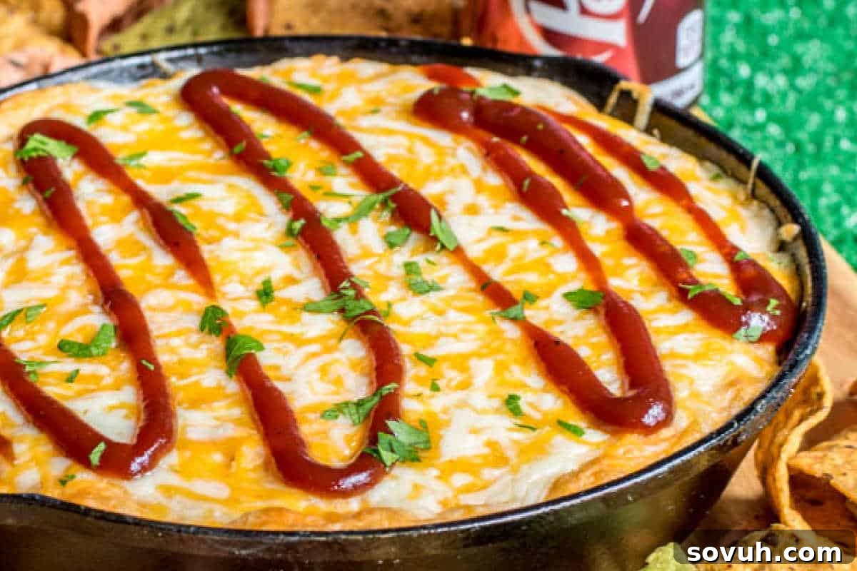 A cast-iron skillet filled with melted cheese topped with BBQ sauce swirls and sprinkled with chopped green herbs, resting on a bed of tortilla chips, creating an enticing visual. This dip looks incredibly creamy and flavorful, ideal for a party spread.