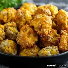 A black bowl filled with baked, golden-brown sausage cheese balls.