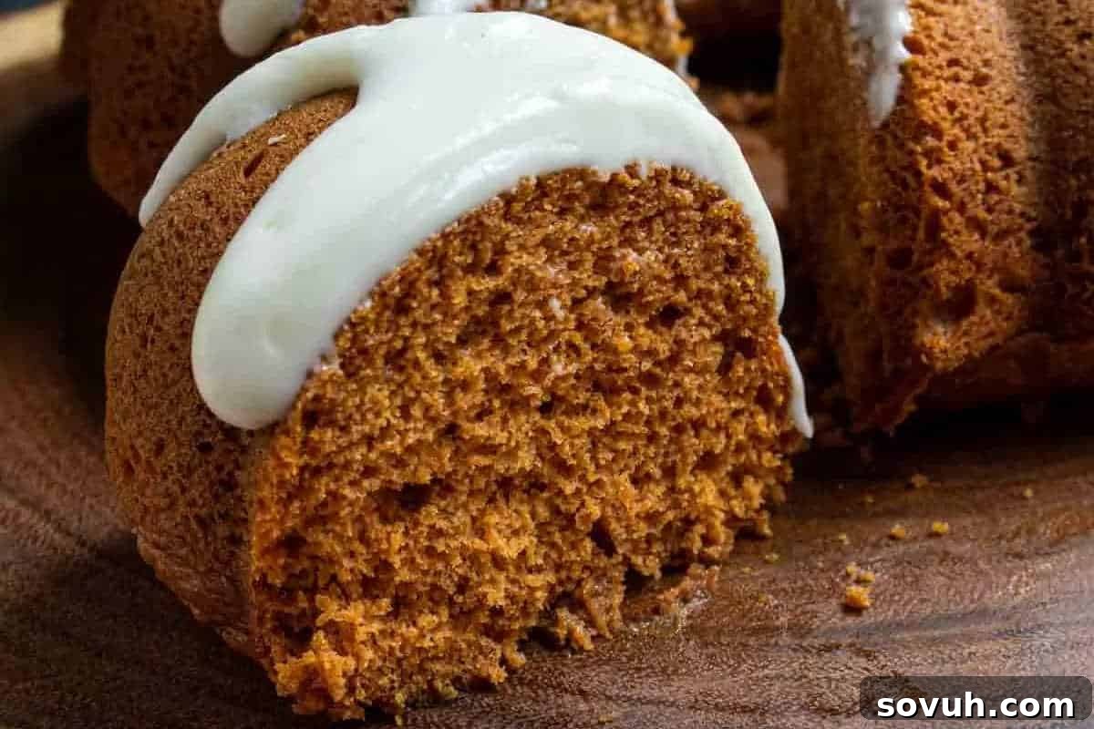 A close-up of a sliced bundt cake with white icing drizzled on top, showcasing one of your tasty creations. Perfect for fall baking, it rests invitingly on a wooden surface.