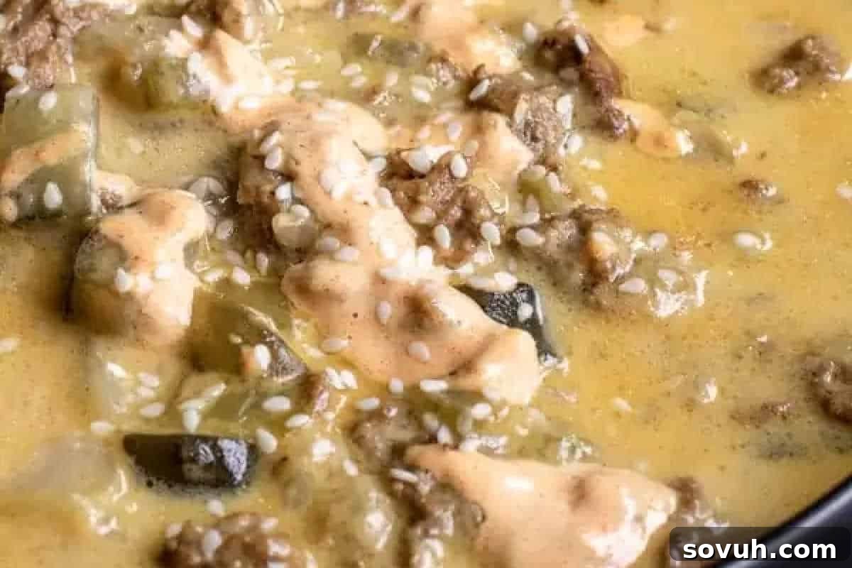 Close-up image of a creamy, yellowish stew with chunks of meat and vegetables, topped with sesame seeds.