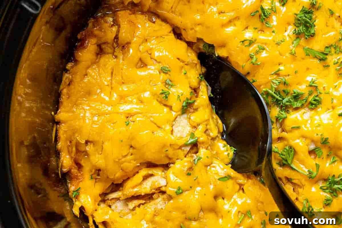 Close-up of a cheesy baked dish with a serving spoon, topped with chopped herbs for garnish.
