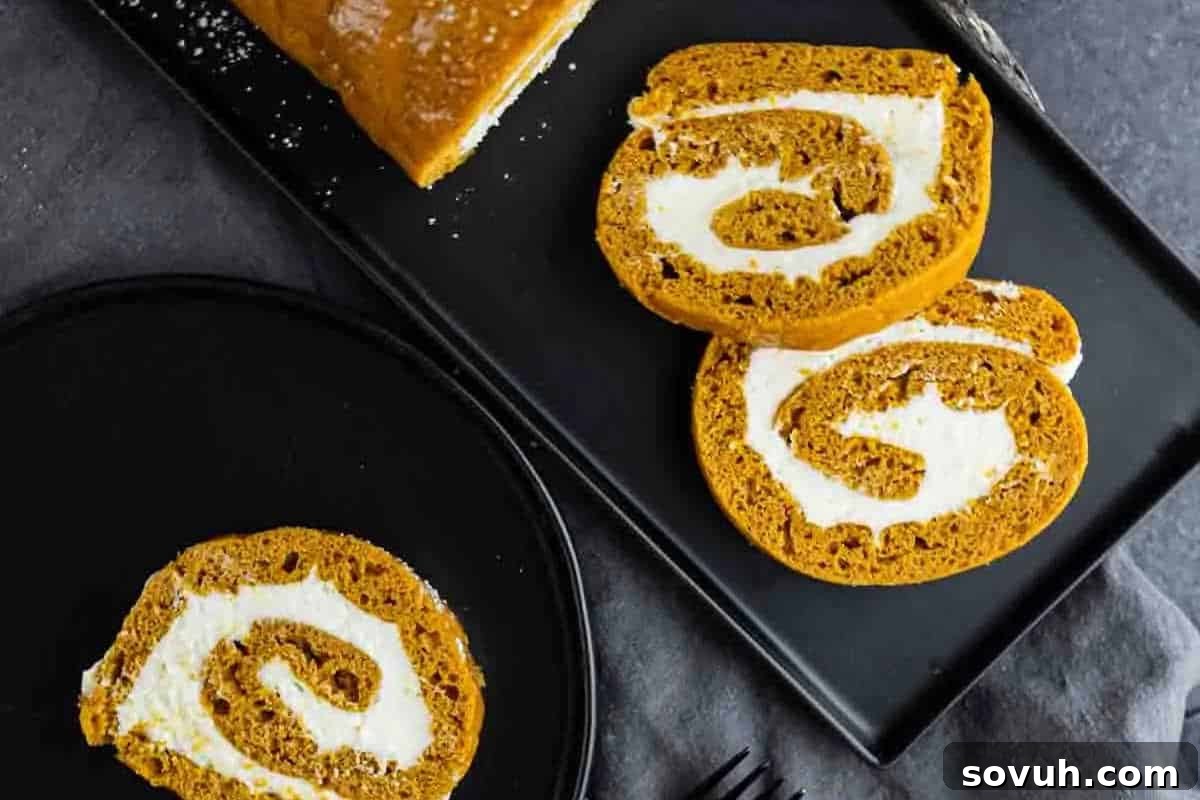 Delicate slices of pumpkin roll cake, featuring a vibrant pumpkin-spiced cake swirled with creamy, sweet filling, elegantly arranged on a sleek black rectangular plate, with an additional slice invitingly placed on a separate round plate.