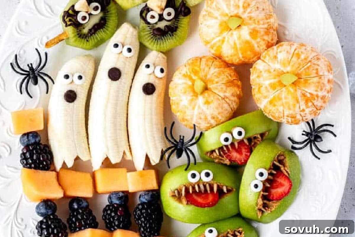 Plate of fruit decorated as Halloween characters: bananas as ghosts, kiwis as monsters, peeled oranges as pumpkins, and fruit skewers with cantaloupe, blackberries, and blueberries.