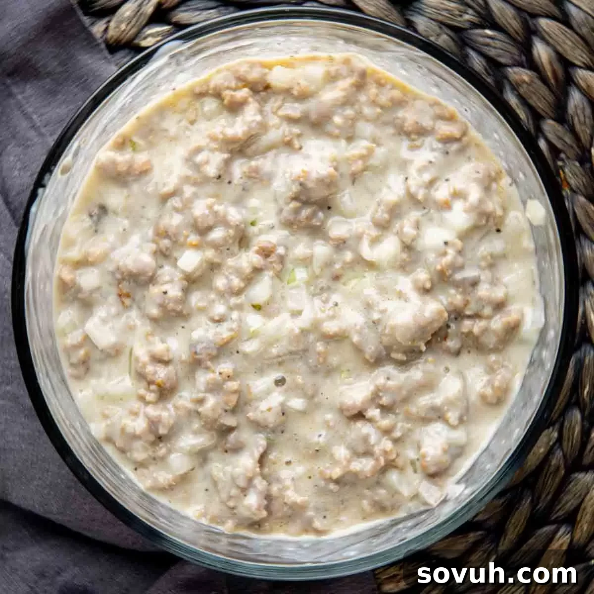 A mixing bowl filled with the creamy, savory sausage mixture, featuring cooked sausage, condensed soup, milk, and seasonings.