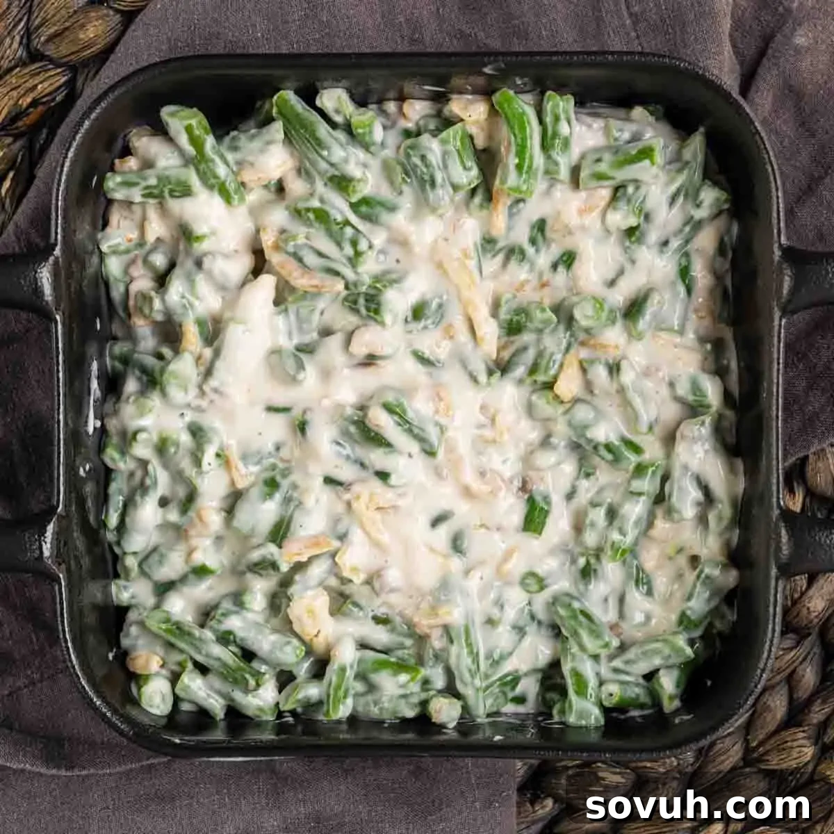 A casserole dish filled with creamy green bean casserole topped with crispy fried onions.