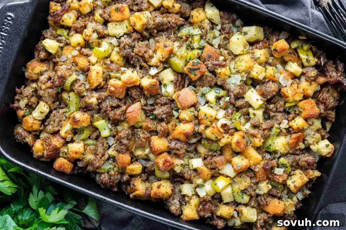 A baking dish filled with sausage and herb stuffing, featuring toasted bread cubes, celery, and seasonings.