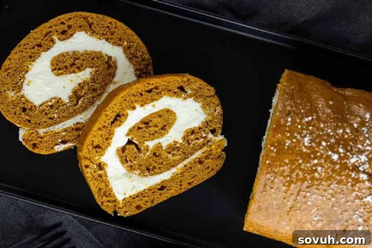 Two slices and a whole pumpkin roll cake filled with cream on a black plate.