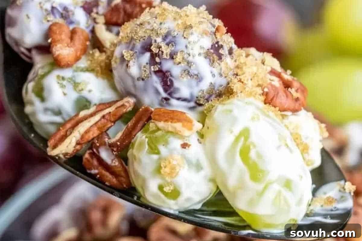 A spoonful of grape salad with creamy dressing, topped with chopped pecans and crushed brown sugar.