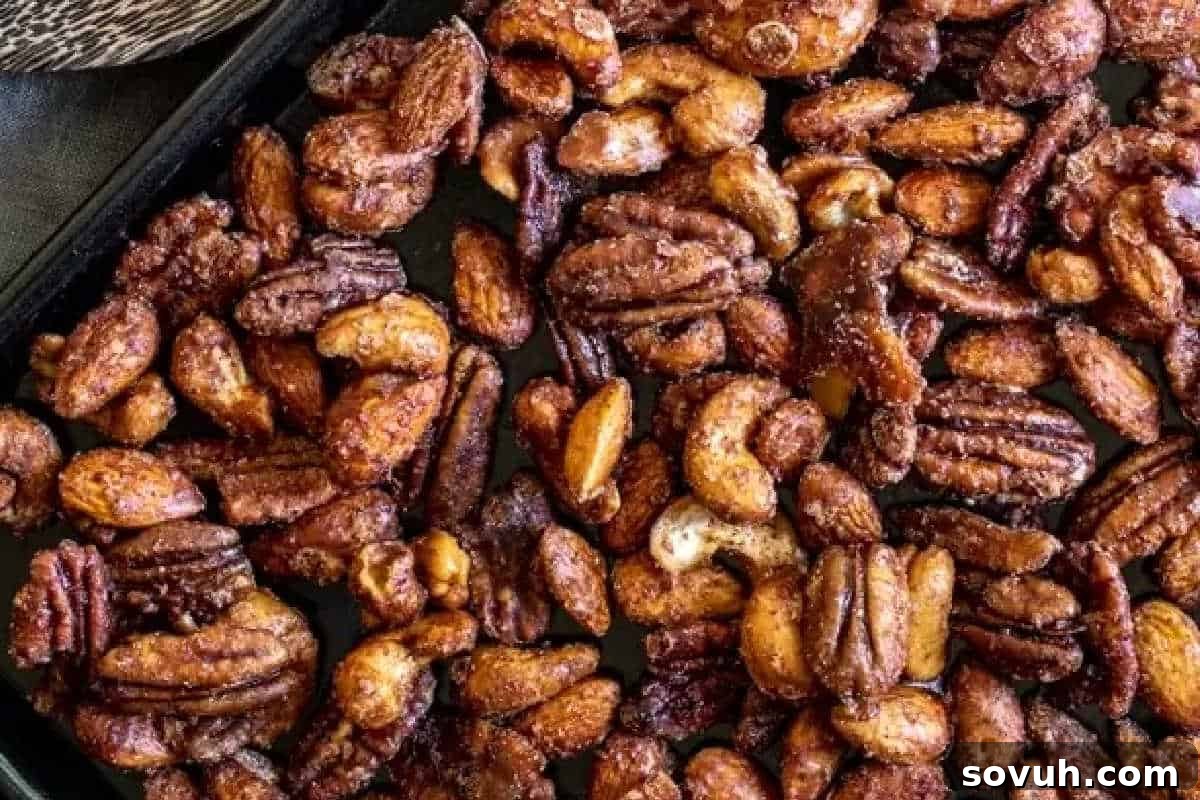 A tray of assorted roasted nuts, including pecans, almonds, and cashews, seasoned and baked.