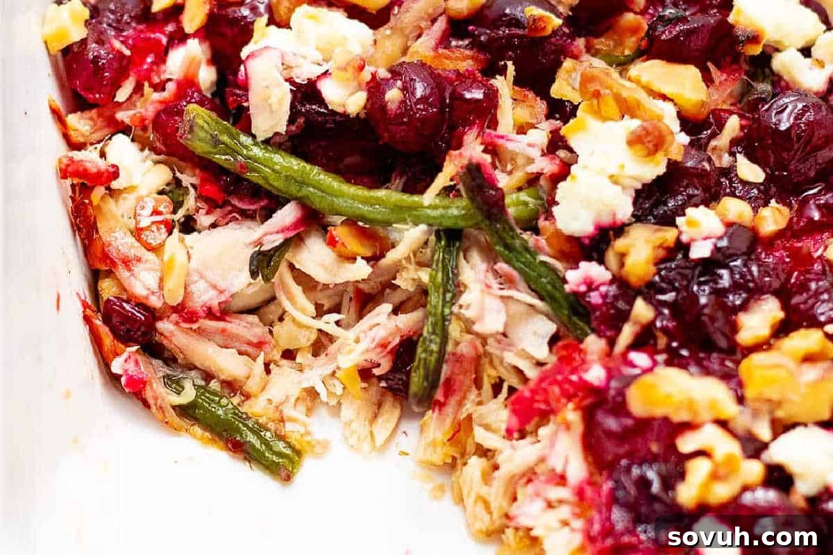 Close-up of a comforting and colorful Leftover Turkey Casserole, showcasing shredded turkey, vibrant green beans, tangy cranberries, crunchy nuts, and melted cheese, all baked together to perfection.