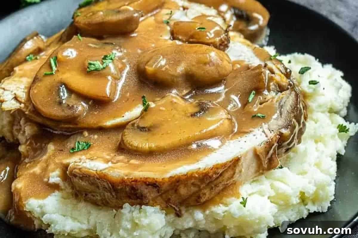 Beautifully sliced turkey breast served generously with a rich mushroom Marsala gravy, resting on a bed of creamy mashed potatoes and garnished with fresh chopped herbs.
