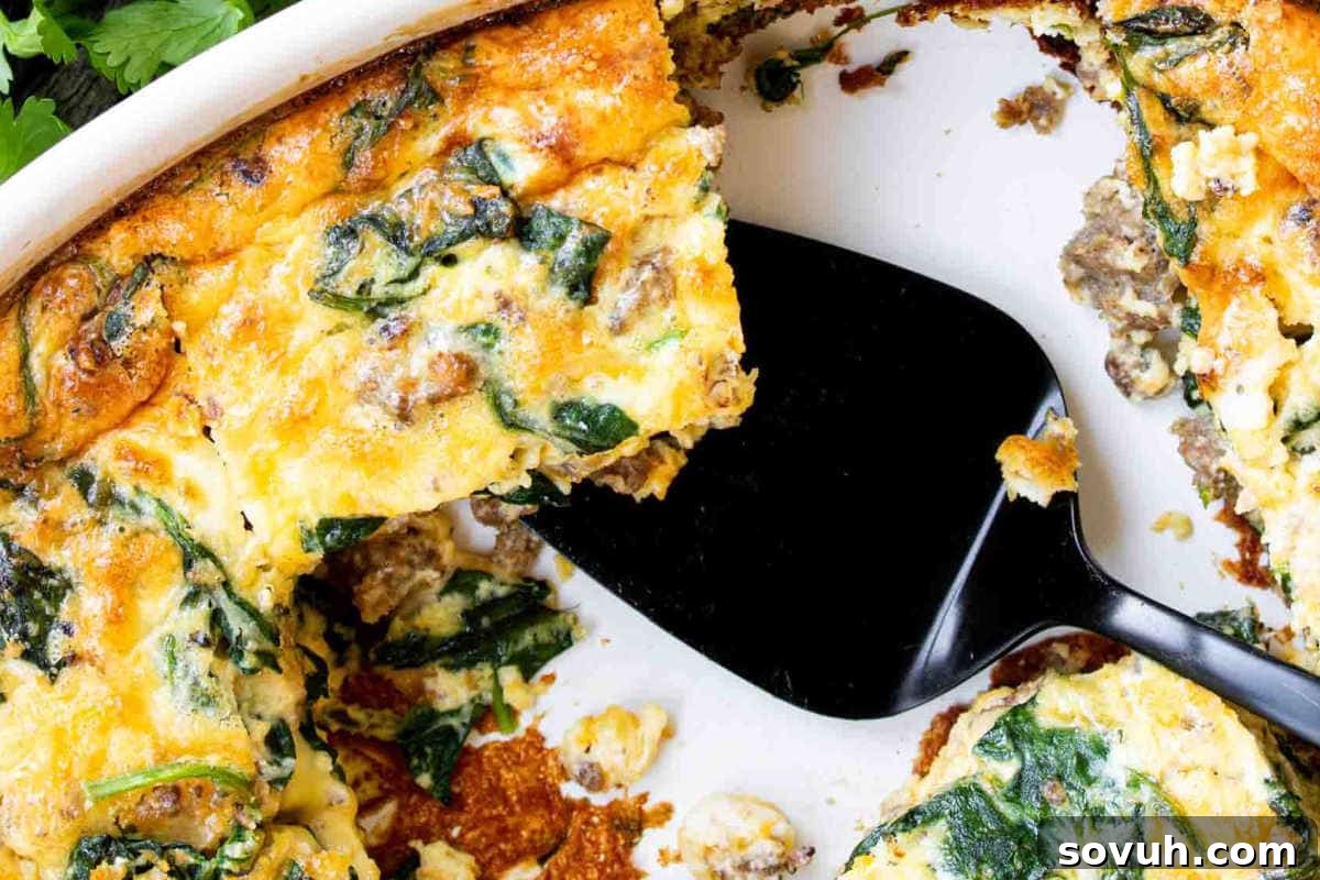 A baked spinach and cheese quiche missing a slice, with a black spatula in the dish, showcasing a healthy breakfast casserole.
