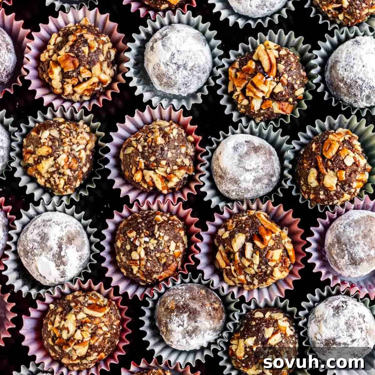 An assortment of chocolate truffles, some rolled in powdered sugar and others in chopped nuts, displayed in paper liners.