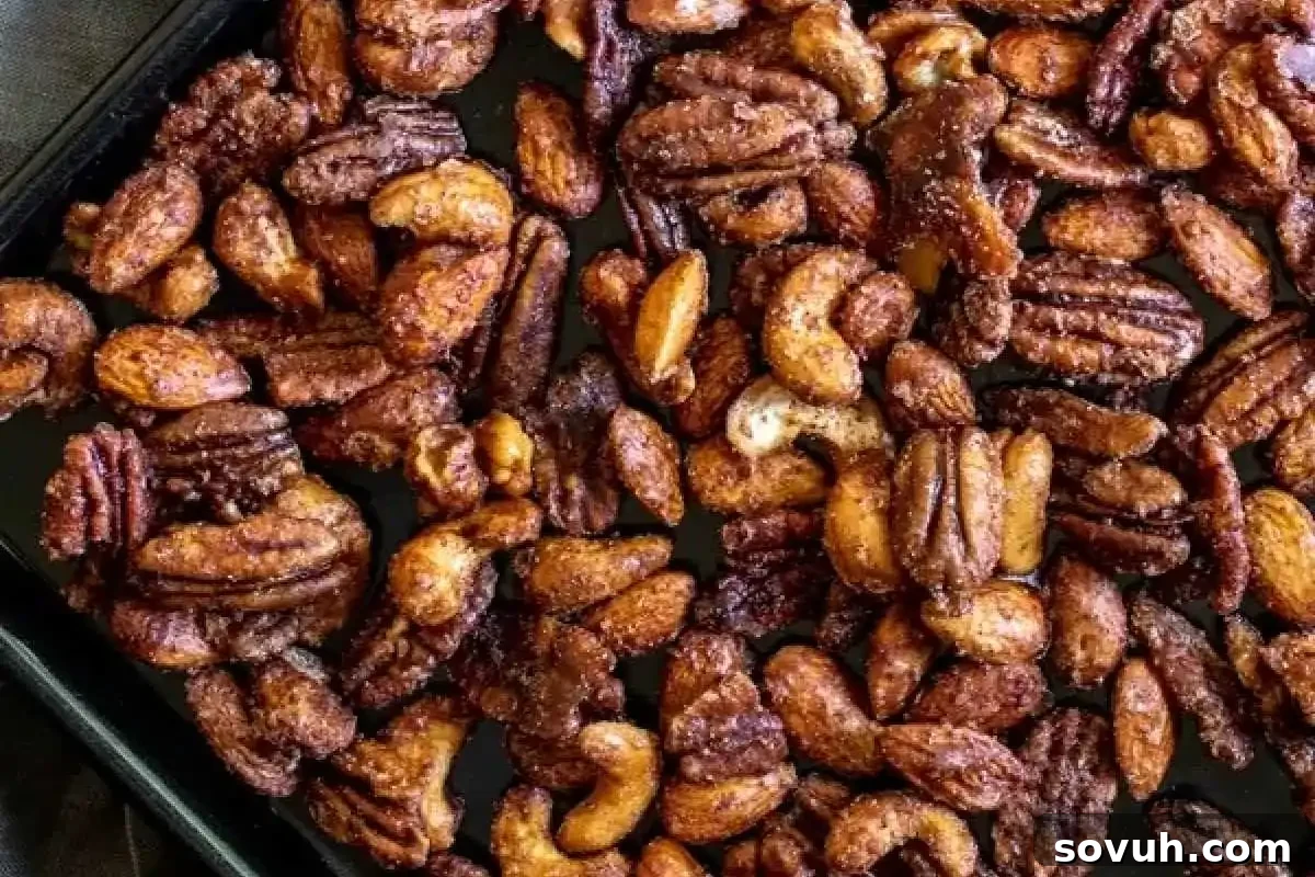A rustic tray generously filled with a medley of roasted pecans and cashews, evenly seasoned with a delightful blend of sweet and savory spices, spread out perfectly for cooling or serving.