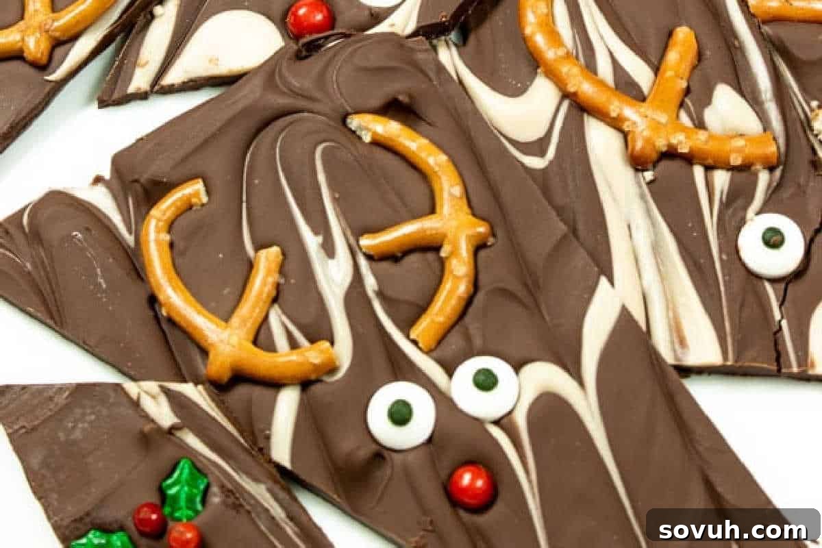 Playful Reindeer Chocolate Bark artfully arranged, each piece uniquely decorated with crunchy pretzel antlers, charming candy eyes, and a bright red candy nose, creating delightful reindeer faces on a bed of rich chocolate.