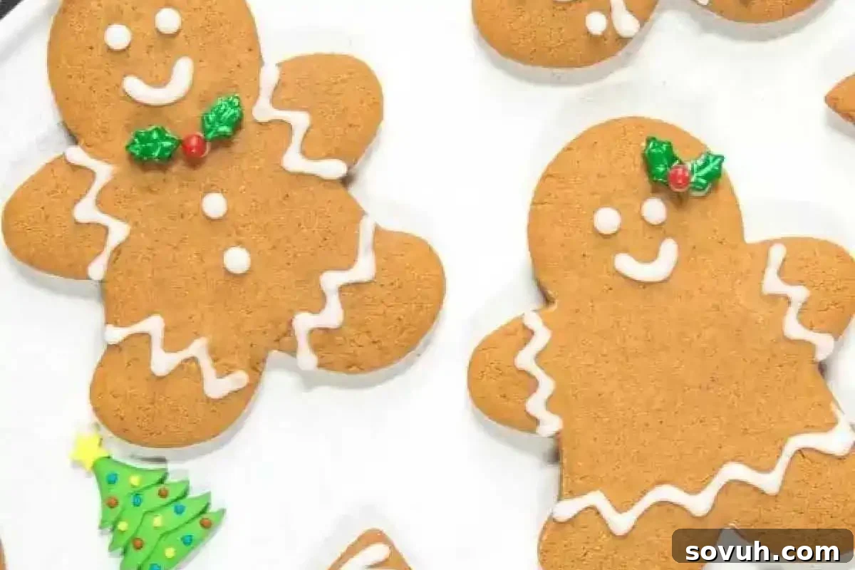 Festive soft gingerbread cookies shaped like people and a tree, adorned with delicate white icing details and small holly decorations.