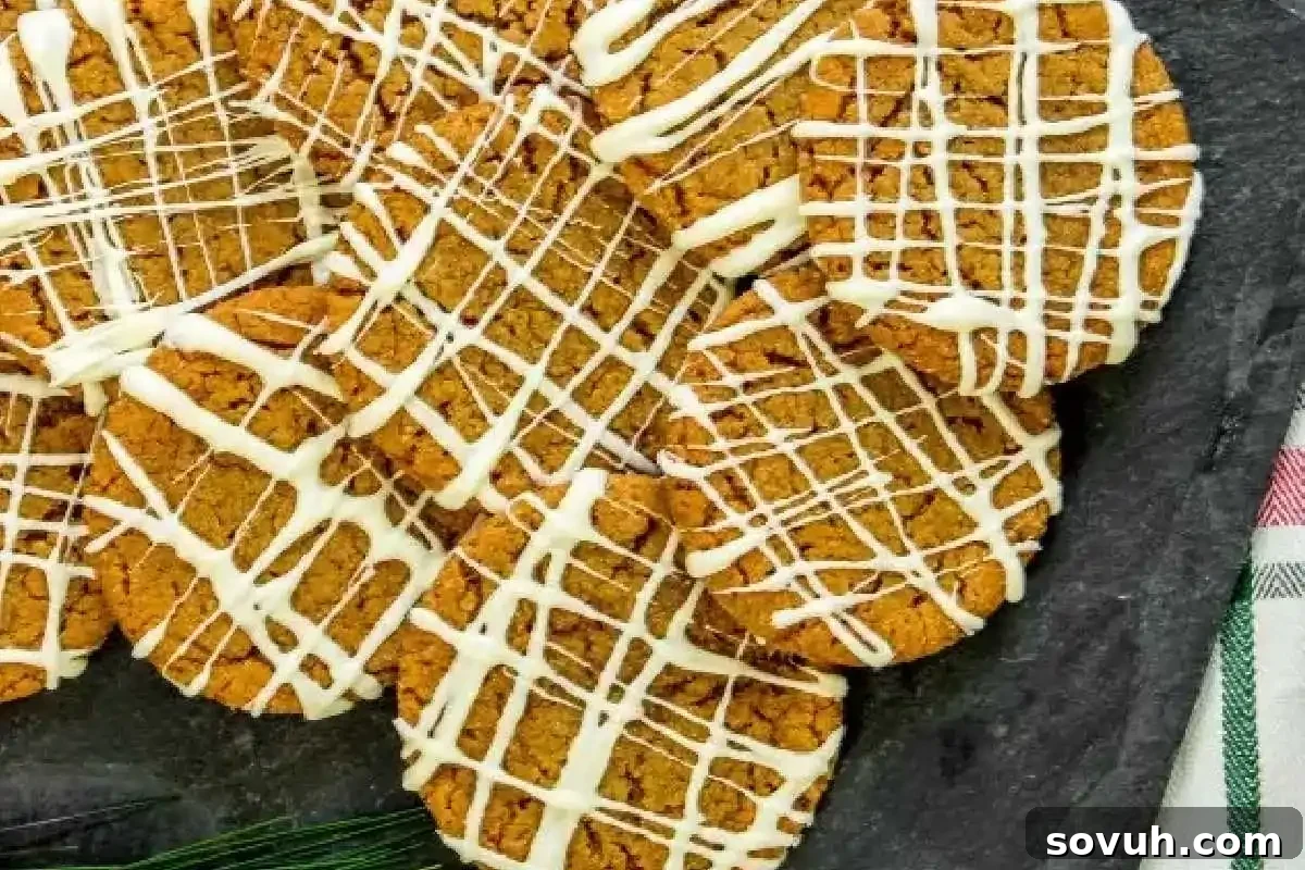 A batch of perfectly baked gingersnap cookies, drizzled with a delicate white icing, presented beautifully on a dark background.