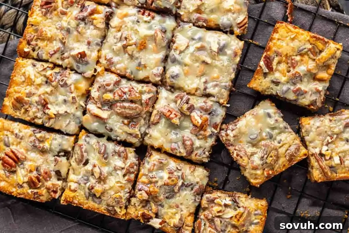 Perfectly cut squares of 7 Layer Bars on a cooling rack, showcasing their distinctive layers including a rich pecan topping and a glossy caramelized finish.