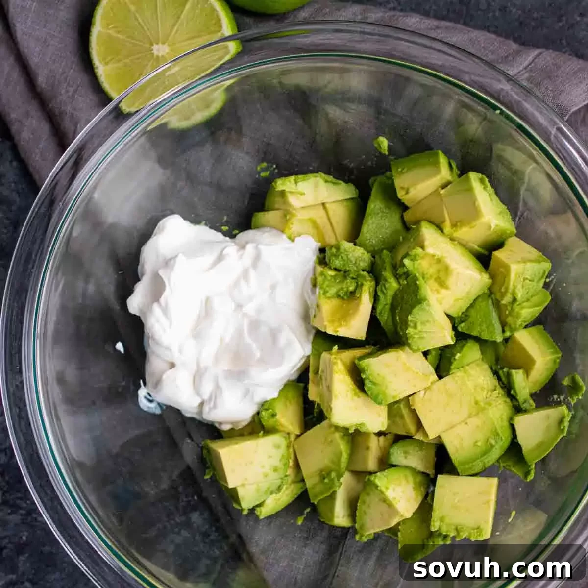 chopped avocado and sour cream in a glass bowl to make Avocado Keto Coleslaw