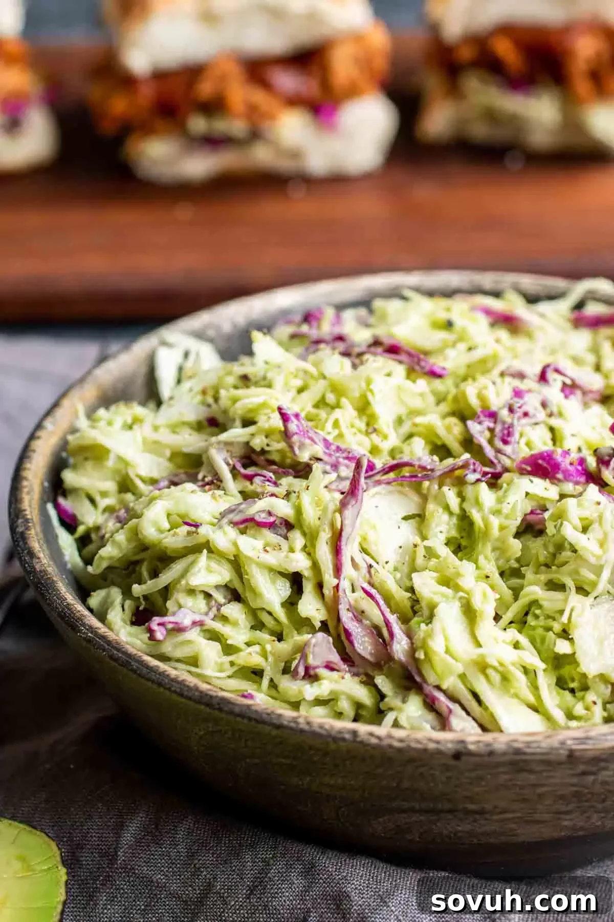 Avocado Keto Coleslaw in wooden bowl with sliders in background