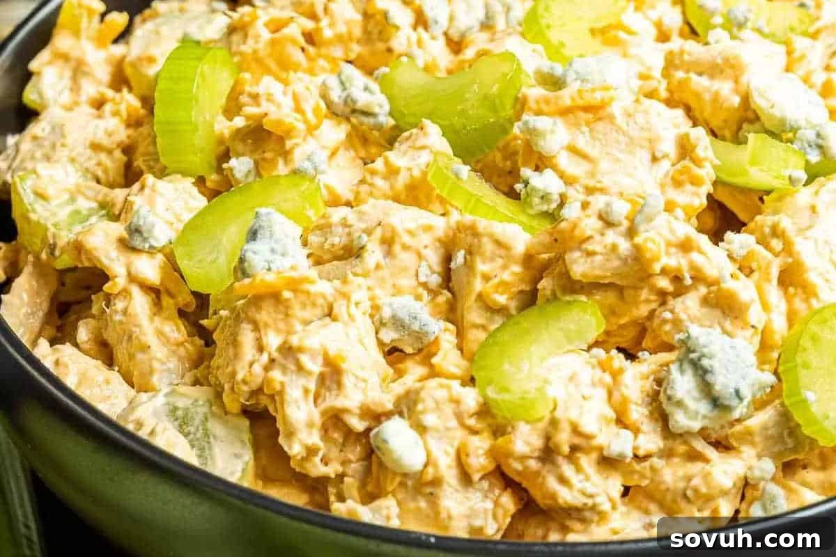 Bowl of chicken salad with buffalo sauce, blue cheese crumbles, and celery slices.