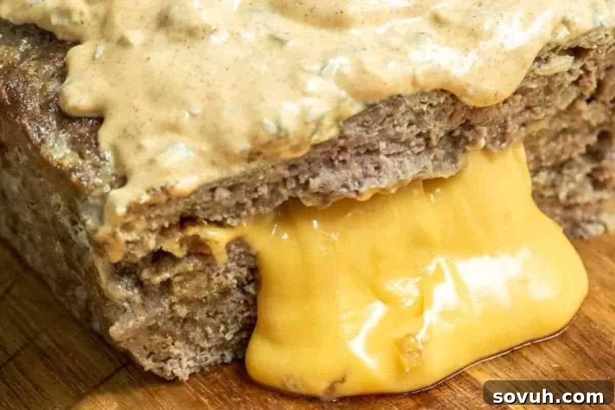 A close-up of golden, melted cheese oozing invitingly from a slice of savory bread, generously topped with a creamy, delectable spread.