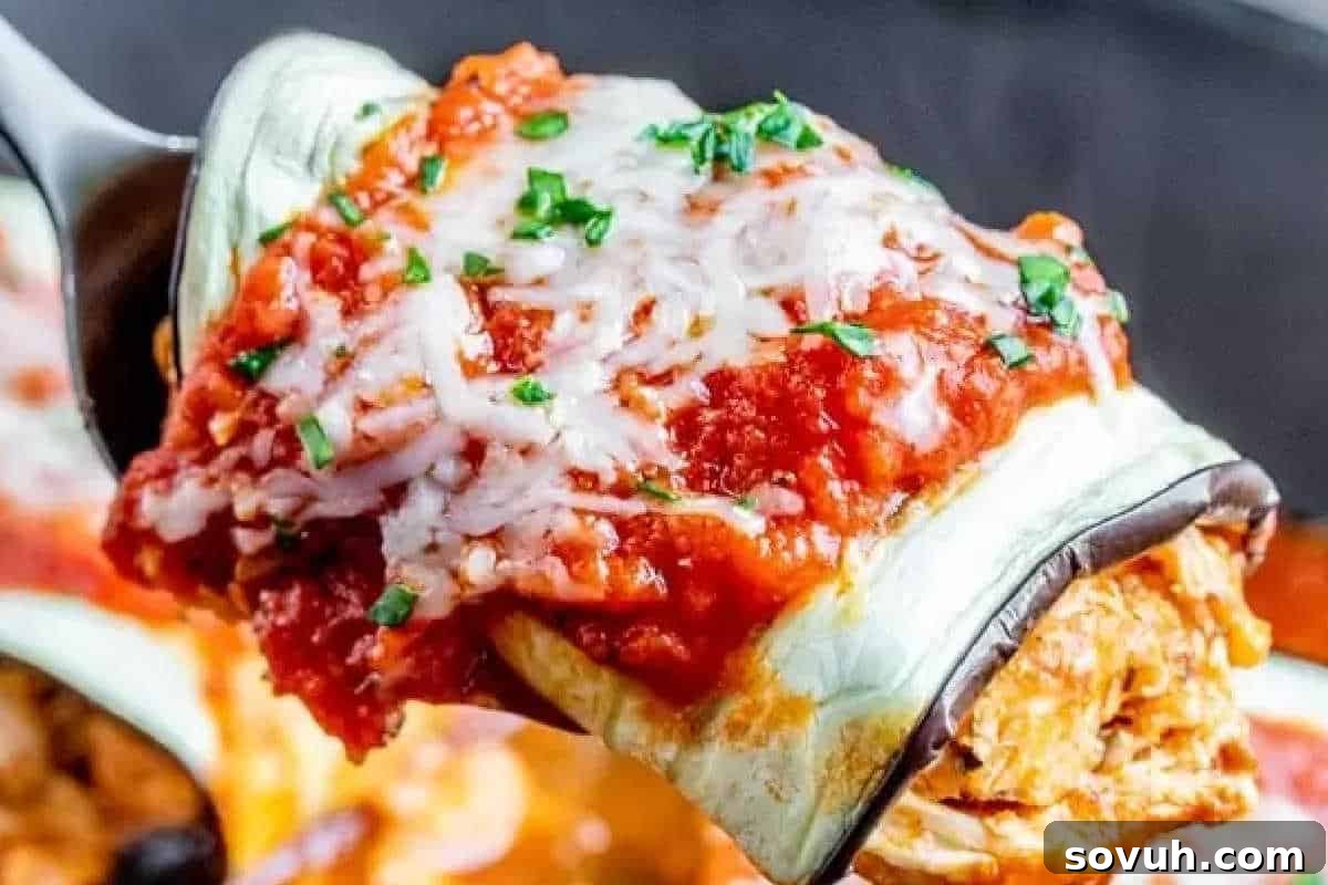 Elegant eggplant rollatini topped with a rich tomato sauce, generous melted cheese, and fresh parsley, served on a convenient serving utensil.