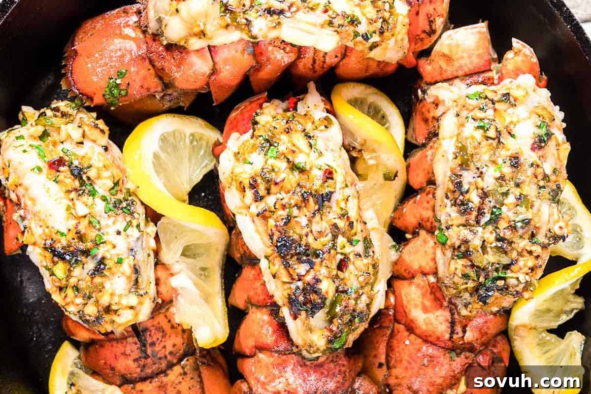 Cooked lobster tails garnished with herbs and garlic, served with lemon wedges, indicating a luxurious yet simple meal.