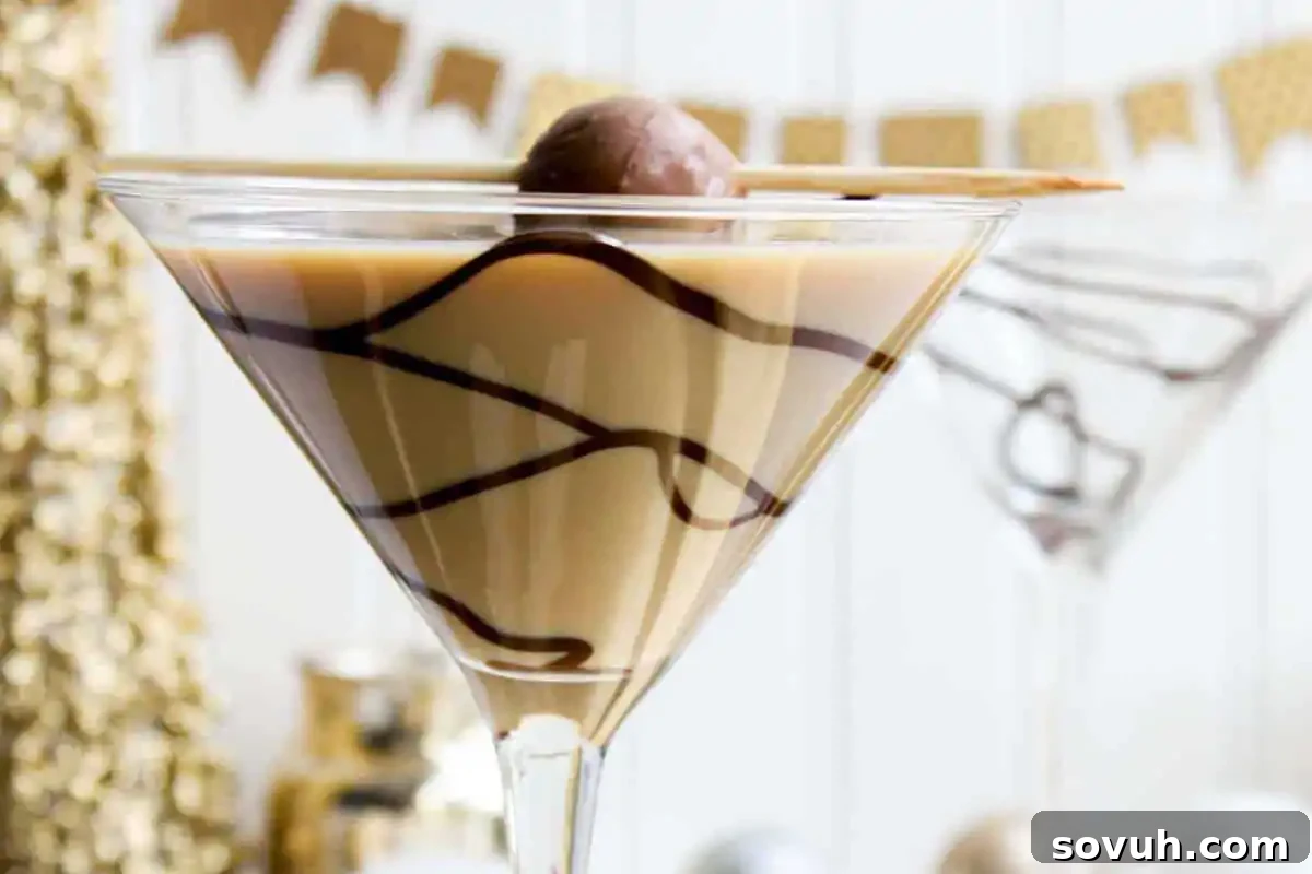 A chocolate martini glass with swirled chocolate syrup, garnished with a chocolate truffle and wafer stick. Blurred decorative background suggests a luxurious dessert experience.