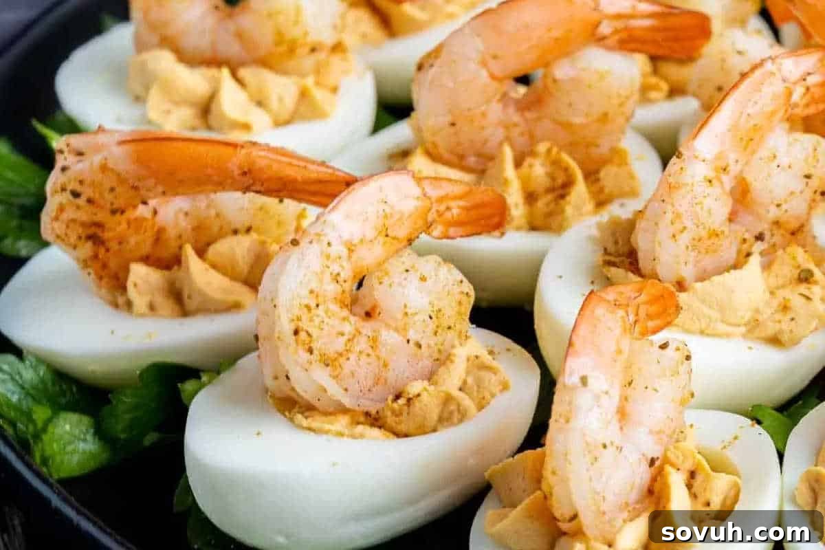 Deviled eggs topped with seasoned shrimp on a bed of greens, offering a sophisticated appetizer for special occasions.