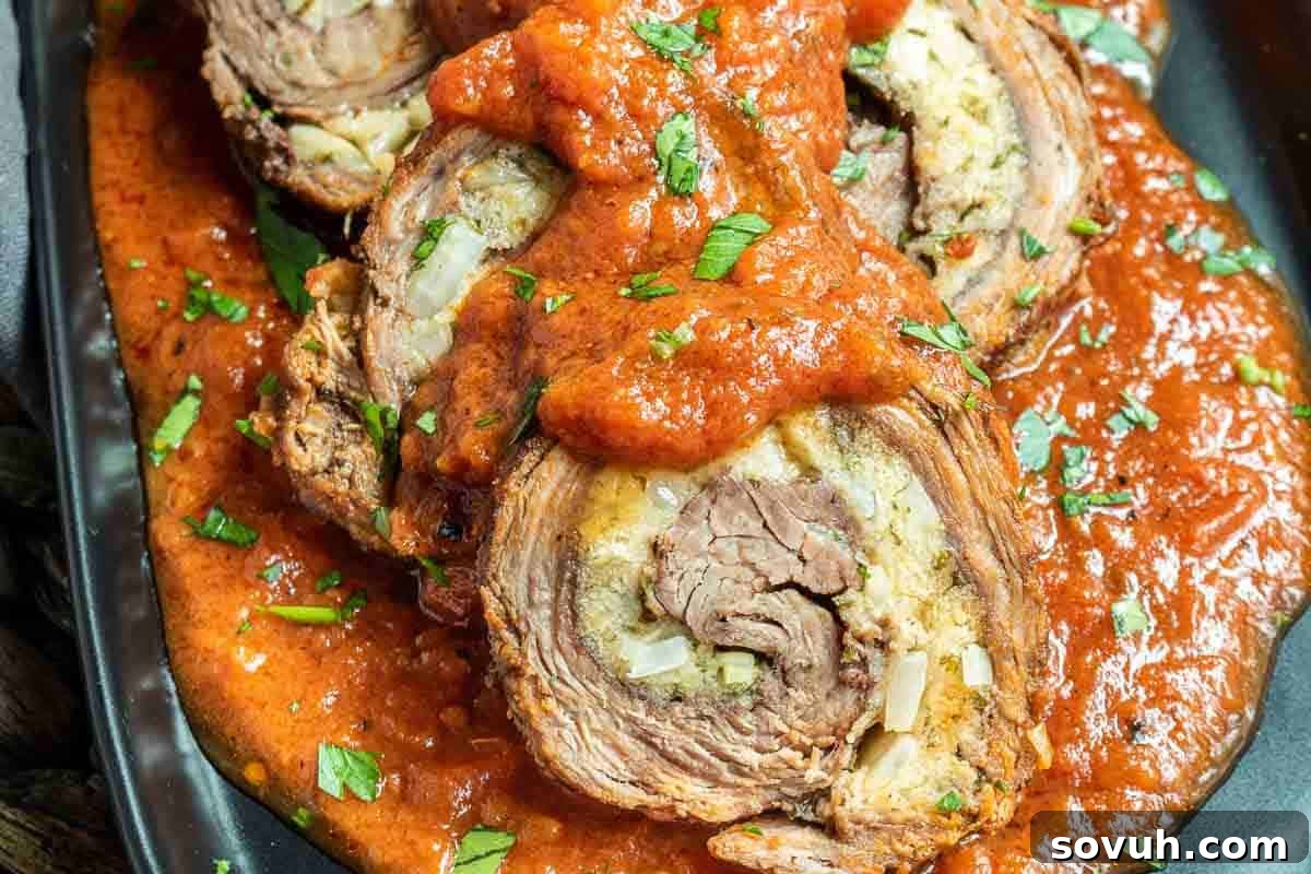 Slices of beef roulade topped with tomato sauce and garnished with chopped herbs on a black plate, showcasing a hearty Italian dish.