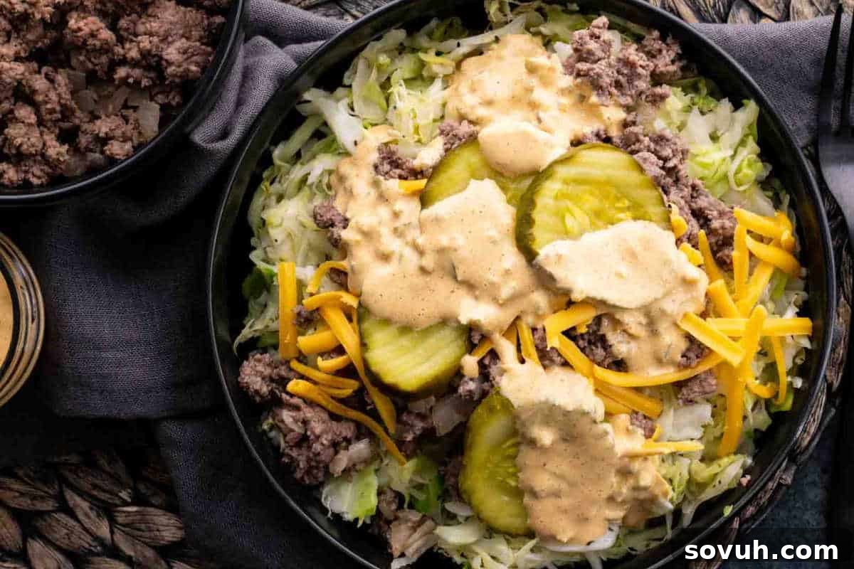A vibrant Big Mac Bowl with a base of crisp shredded lettuce, topped with perfectly cooked ground beef, generous sprinkles of shredded cheddar cheese, tangy pickle slices, and a creamy, zesty Big Mac-style dressing.