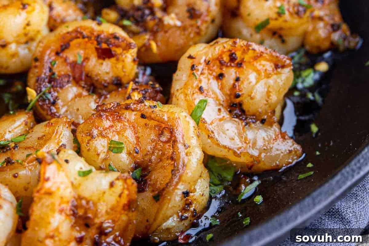 Close-up of cooked shrimp seasoned with spices and herbs in a skillet.