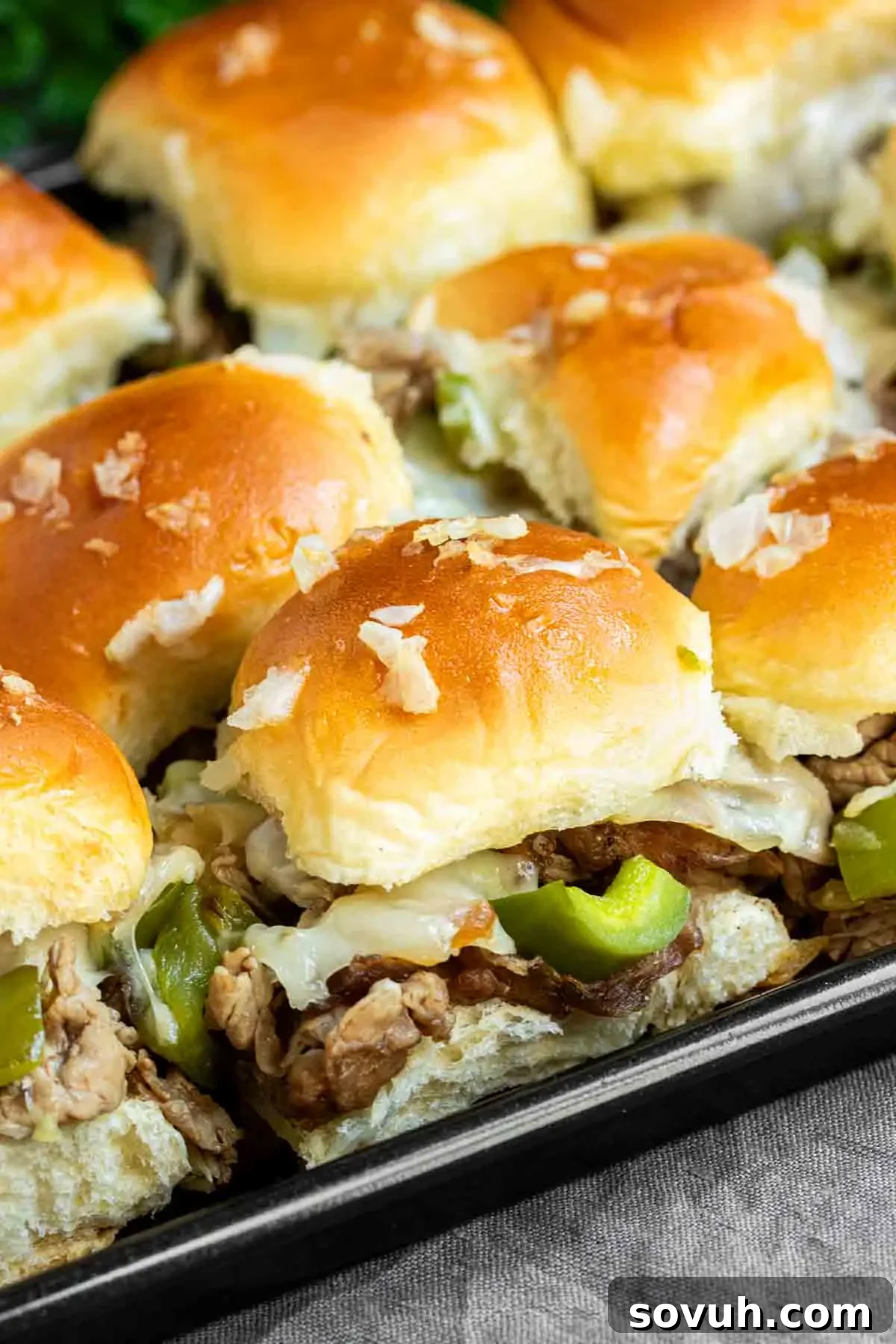A vibrant tray of Philly Cheesesteak Sliders garnished with colorful peppers and onions, ready for serving.