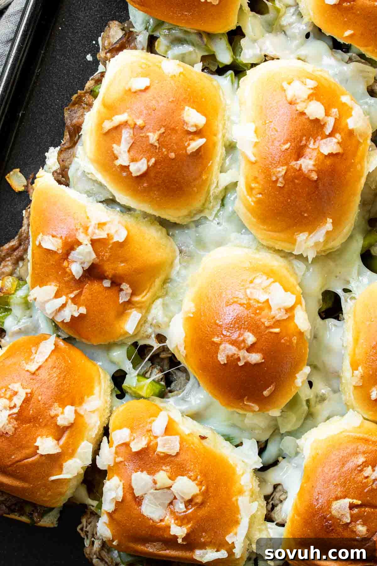 Philly Cheesesteak Sliders arranged neatly on a baking sheet, fresh out of the oven and ready to be served.