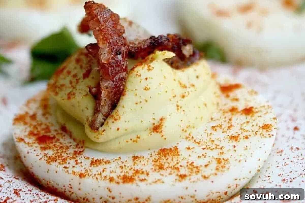A deviled egg topped with crispy bacon and sprinkled with paprika.