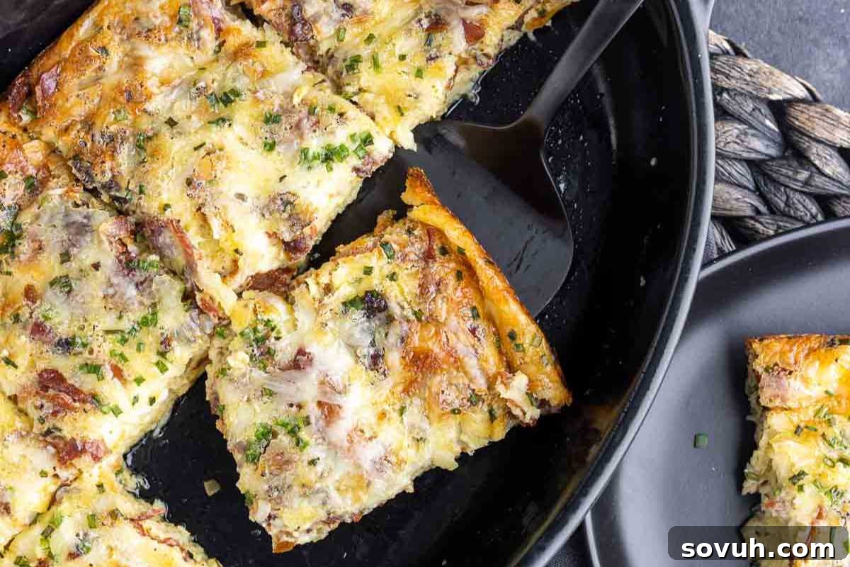 Slices of a golden-brown crustless quiche Lorraine with herbs and bacon served in a skillet and on a black plate, with a spatula.