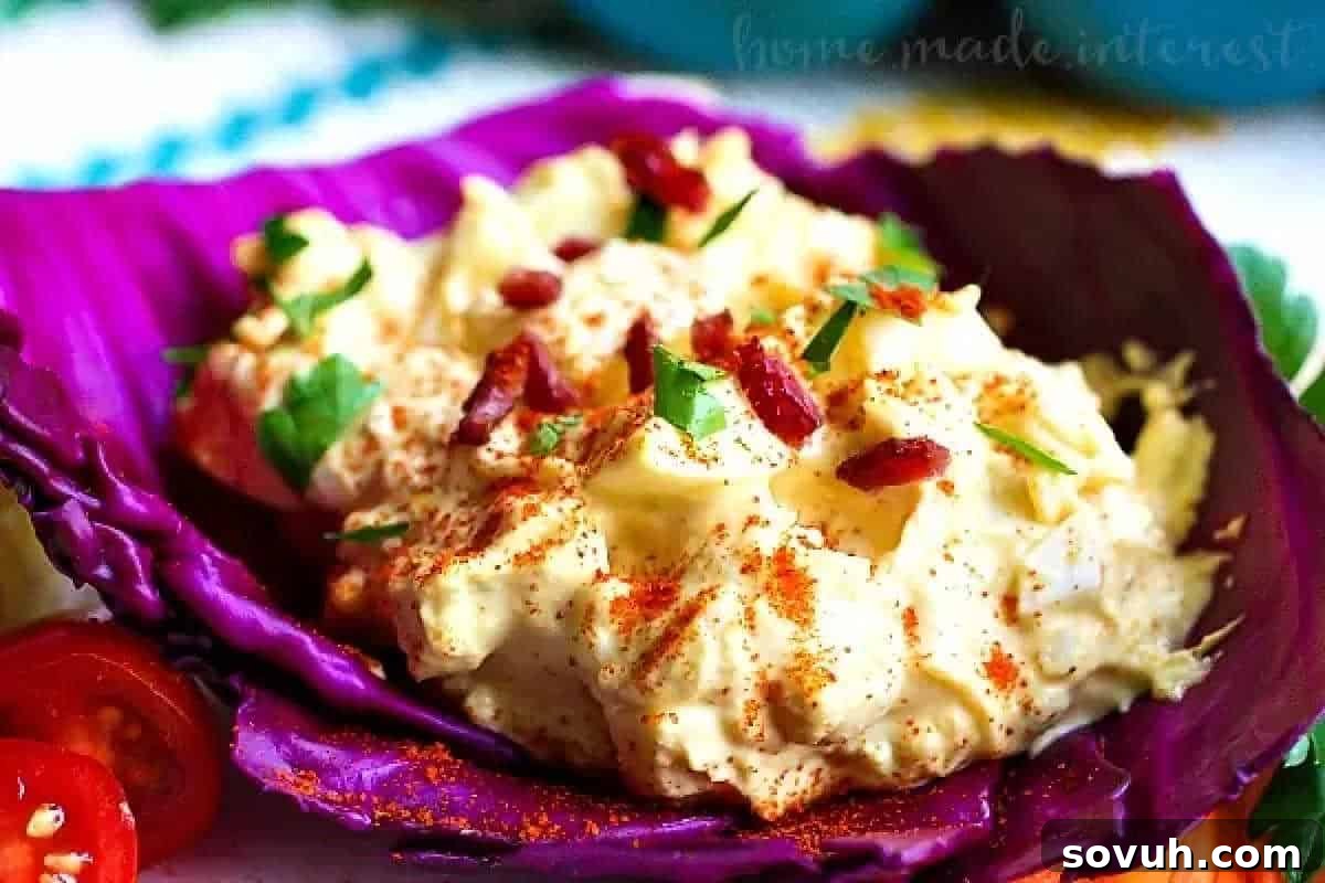 Potato salad with bacon bits and herbs, served in a purple cabbage leaf and garnished with paprika, makes for a delicious brunch favorite.