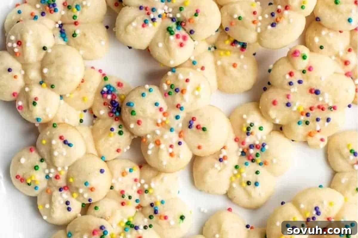 Whimsical Easter Treats Made Simple 12 A pile of flower-shaped cookies with colorful sprinkles on a white background.