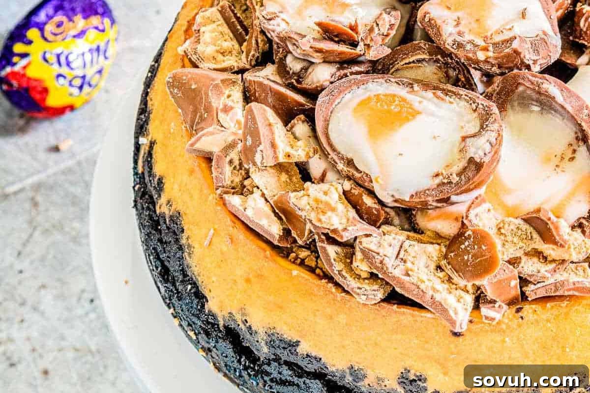Whimsical Easter Treats Made Simple 3 Cheesecake topped with halved creme-filled chocolate eggs and chocolate pieces on a white plate. A wrapped creme egg is visible in the background.