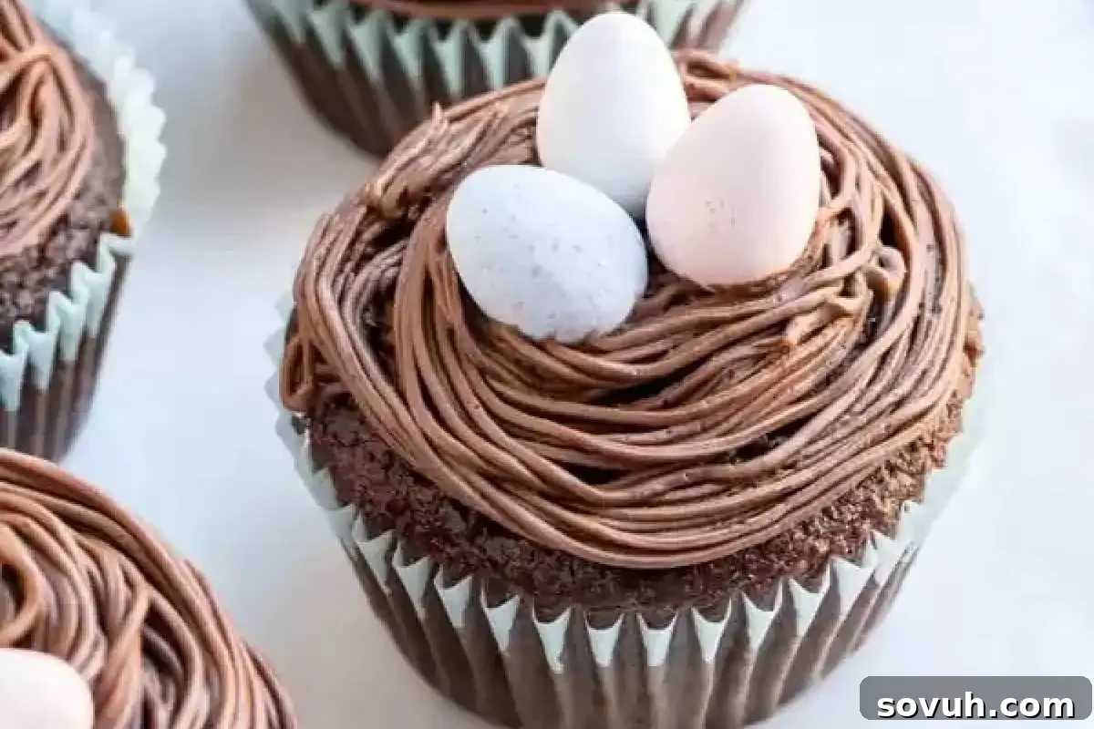 Whimsical Easter Treats Made Simple 4 Chocolate cupcake with brown frosting resembling a nest, topped with three small, egg-shaped candies.