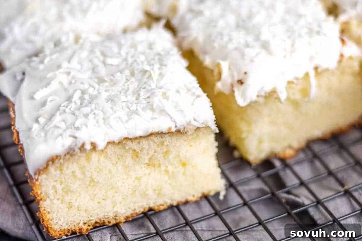 Slices of vanilla sheet cake with white frosting and shredded coconut on a wire cooling rack.