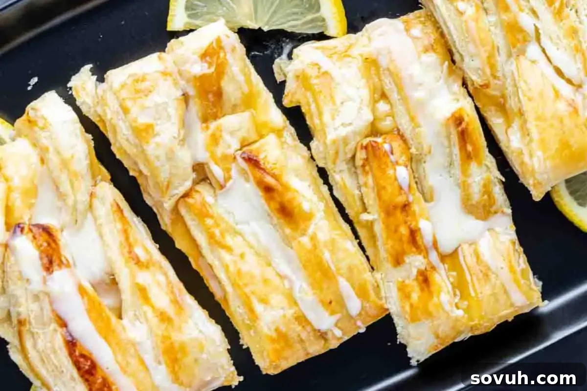 Lemon Danish braid drizzled with icing on a black plate. 