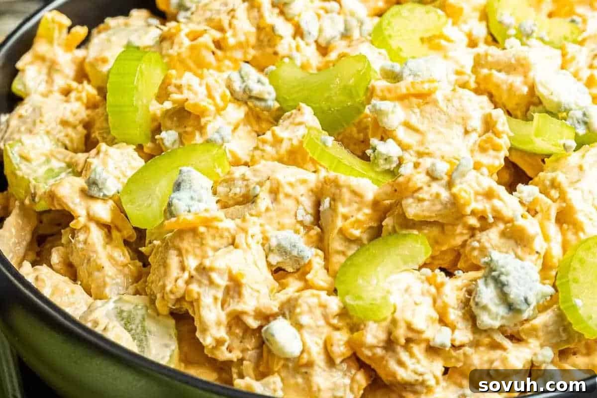 Close-up of a vibrant buffalo chicken salad in a bowl, featuring generous chunks of seasoned chicken, crisp sliced celery, tangy blue cheese crumbles, and a creamy, zesty dressing that coats every ingredient.