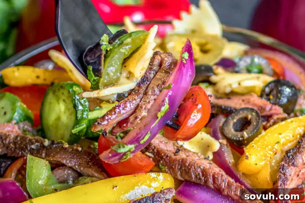 A hearty Steak Fajita Pasta Salad featuring tender grilled steak strips, bell peppers, onions, and pasta tossed in a zesty fajita dressing, served in a rustic bowl.
