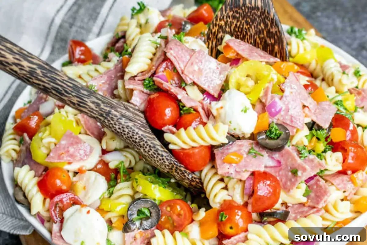 A vibrant Italian Pasta Salad overflowing with colorful rotini pasta, fresh mozzarella balls, salami, olives, cherry tomatoes, and bell peppers, all glistening with a tangy Italian dressing.