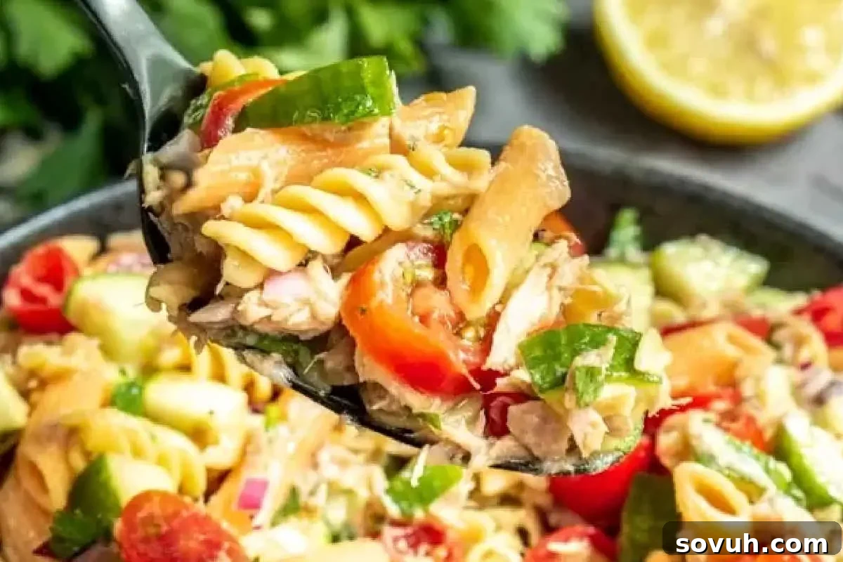 A light and healthy Tuna Pasta Salad without mayo, featuring pasta, flaked tuna, diced vegetables like bell peppers and onions, and a vibrant vinaigrette dressing, served in a bowl with fresh herbs.
