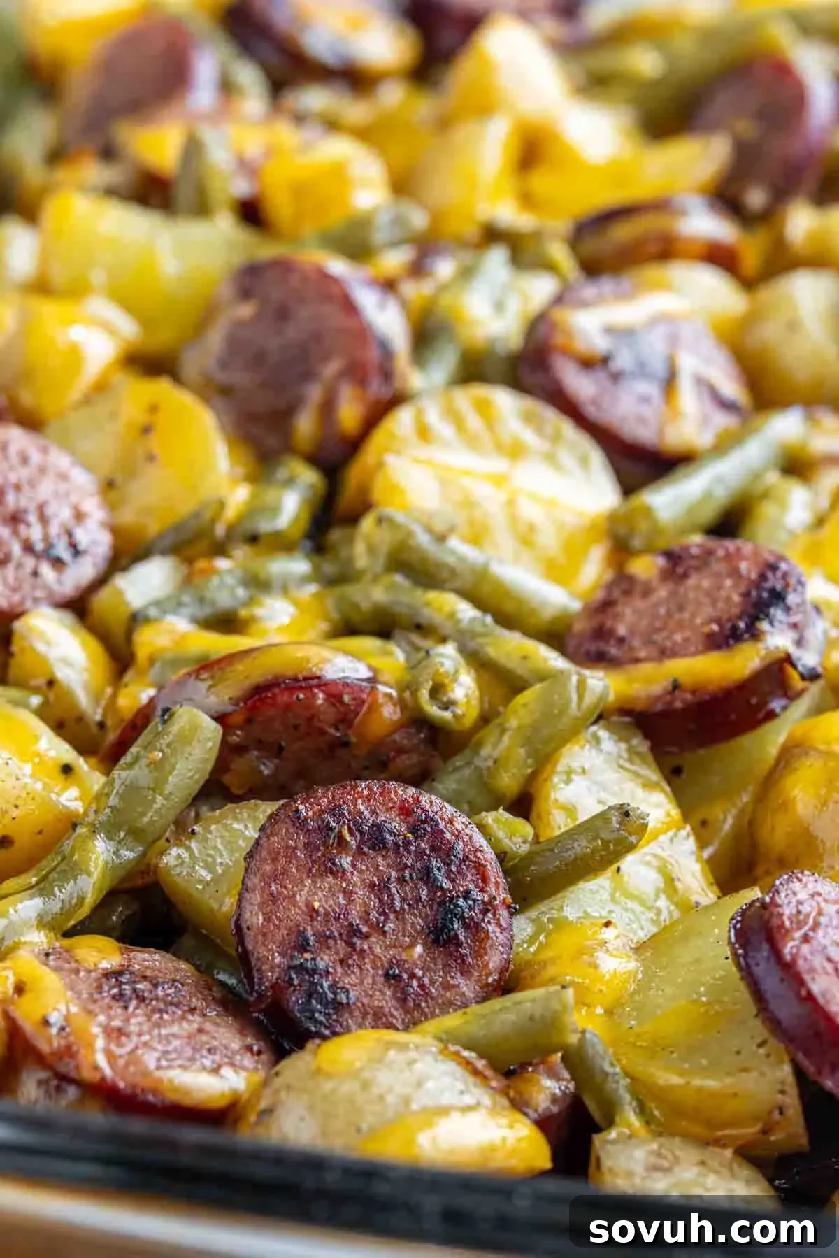 Hearty Sausage, Potato, and Green Bean Bake 5 Sliced sausage, green beans, and potatoes baked together with melted cheese on top.